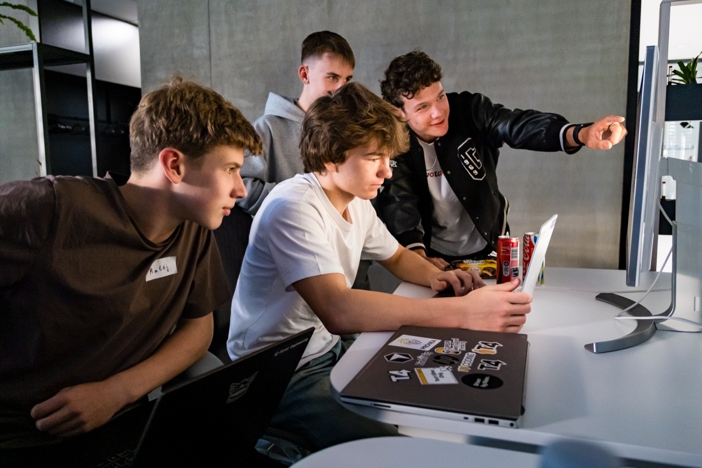 Four people gathered at one workstation during the build sprint, one pointing at a monitor